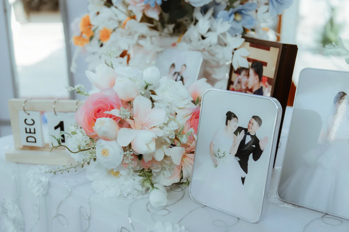 Charming wedding table arrangement with photos, fresh flowers, and a date block showing December.