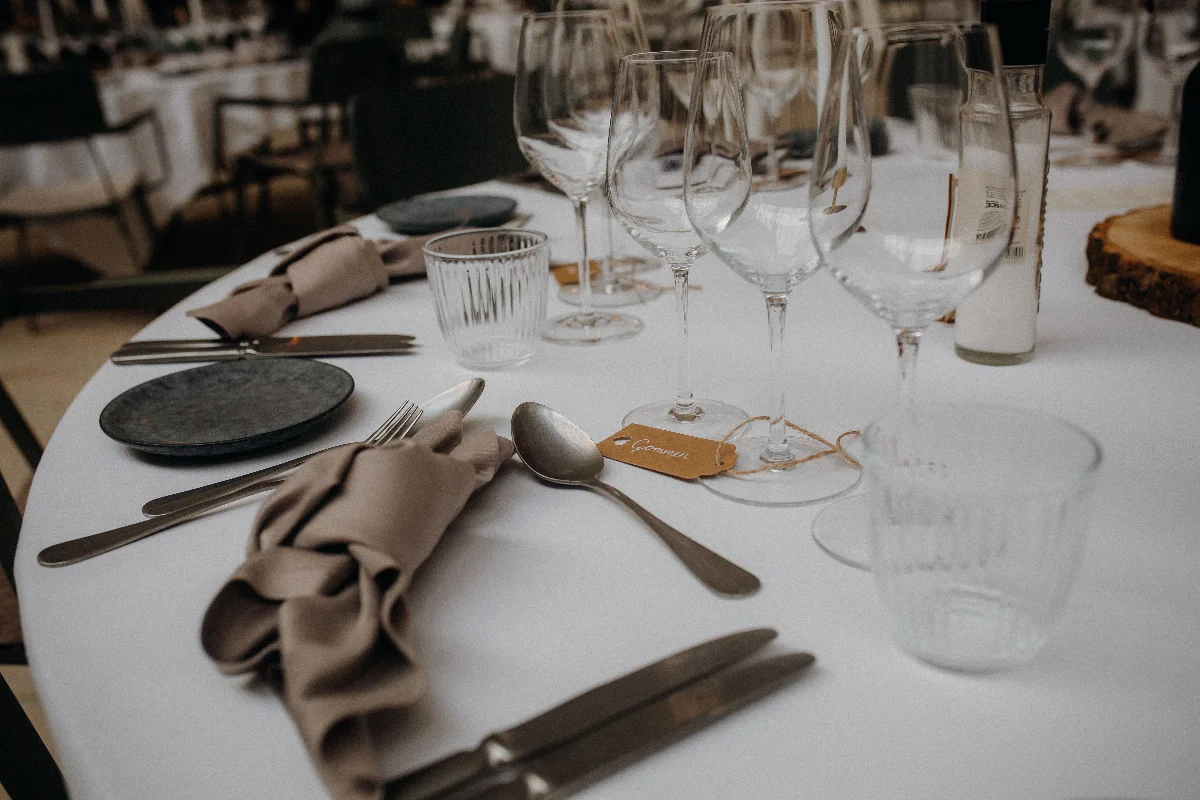 A sophisticated table setup featuring glasses, utensils, and napkins on a white tablecloth.