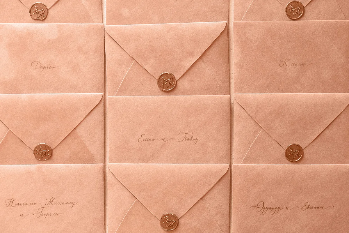 Rows of peach-colored envelopes sealed with wax, featuring elegant calligraphy.