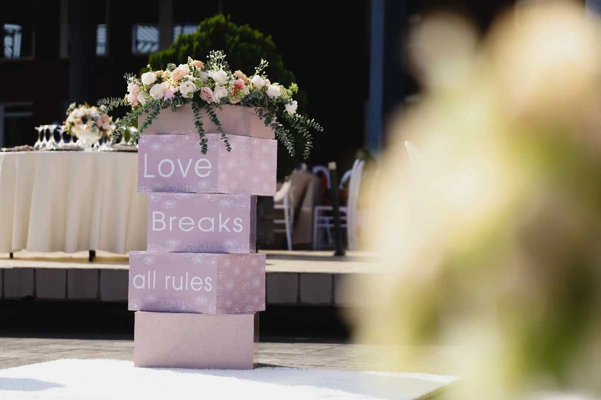 Outdoor wedding setting with floral decorations and "Love Breaks all rules" signage.