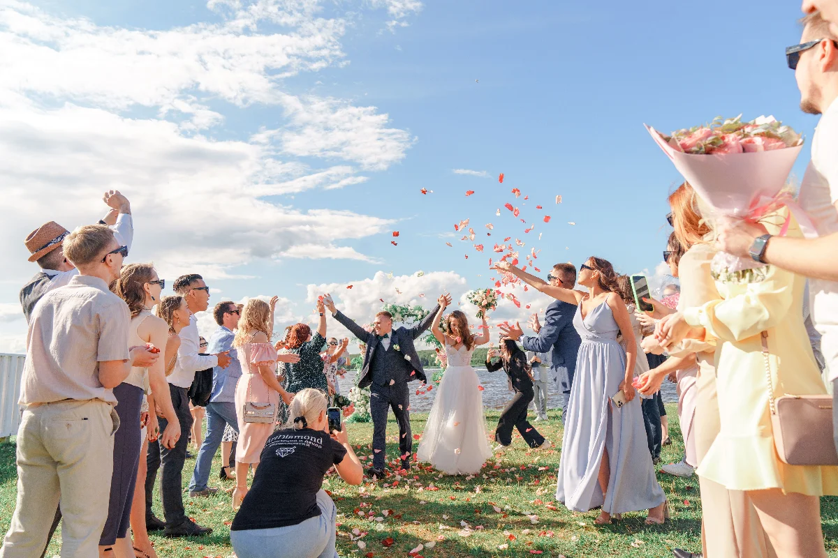 A joyful outdoor wedding celebration with a bride and groom surrounded by guests and confetti.