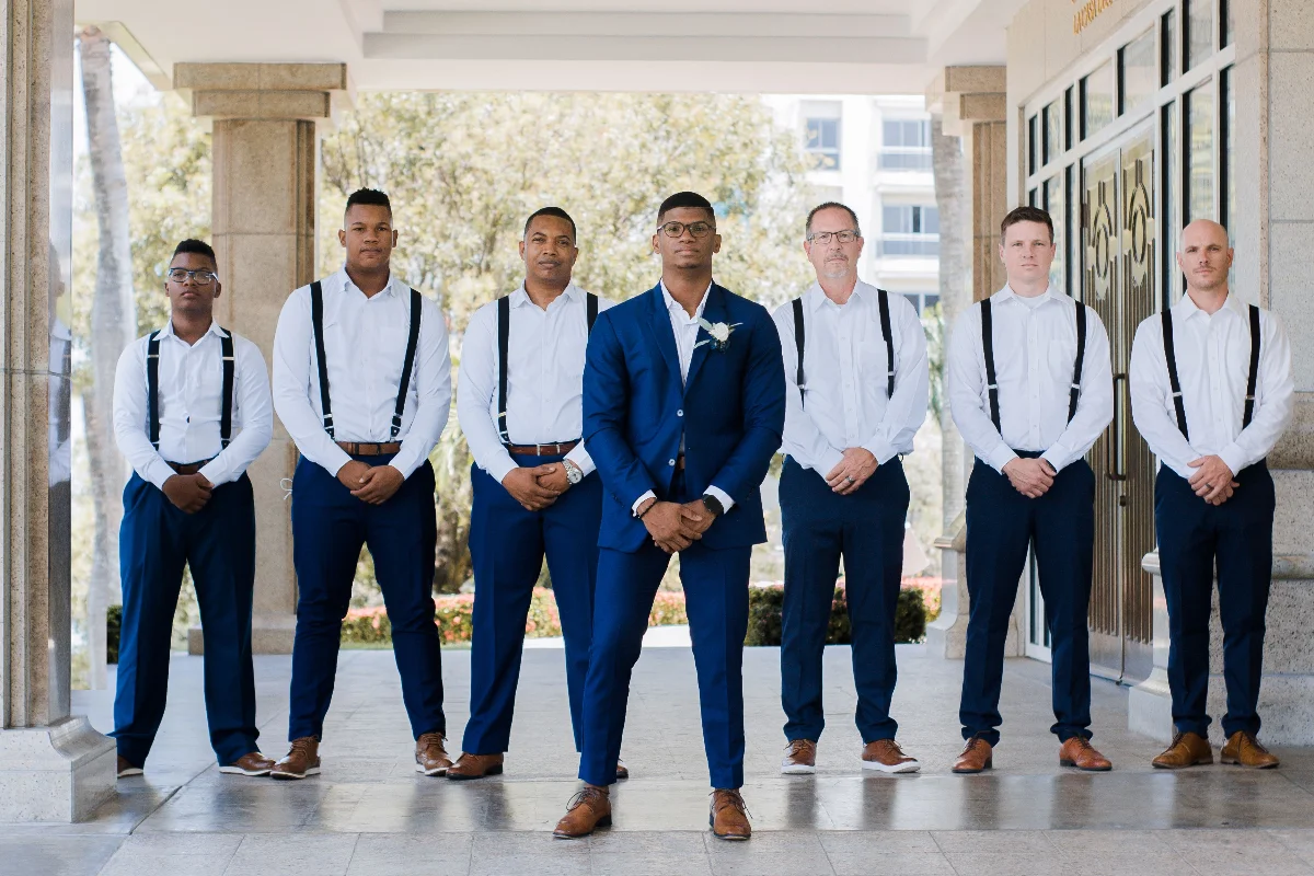A group of groomsmen posed elegantly outside a wedding venue in matching suits.
