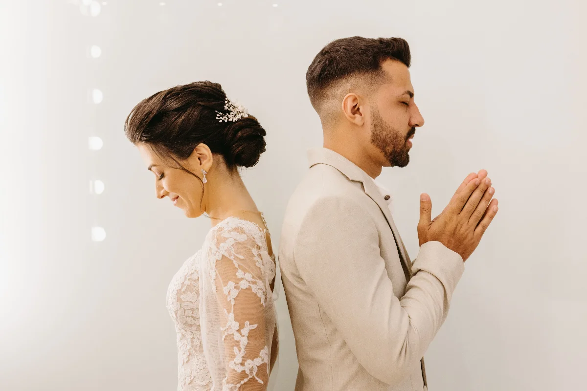 Bride and groom share a tender first touch moment before their wedding ceremony, emphasizing elegance and romance.