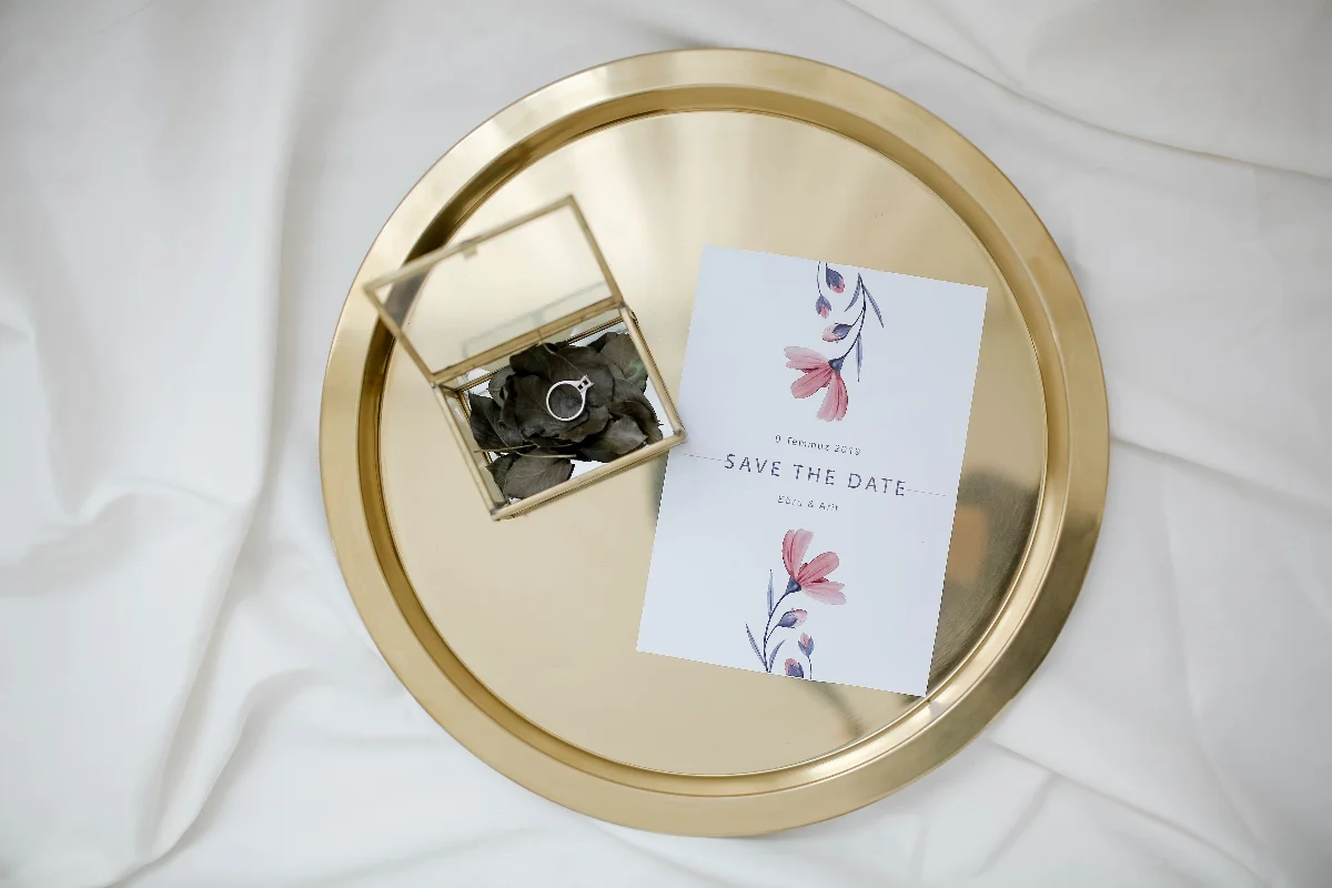 An elegant save the date card and engagement ring on a gold tray, perfect for weddings.