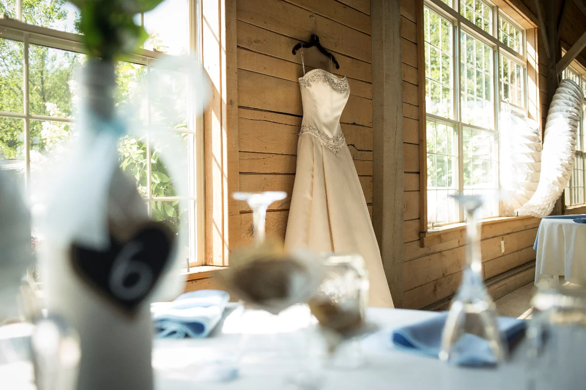 A beautiful wedding dress hanging in a rustic sunlit venue, perfect for natural weddings.
