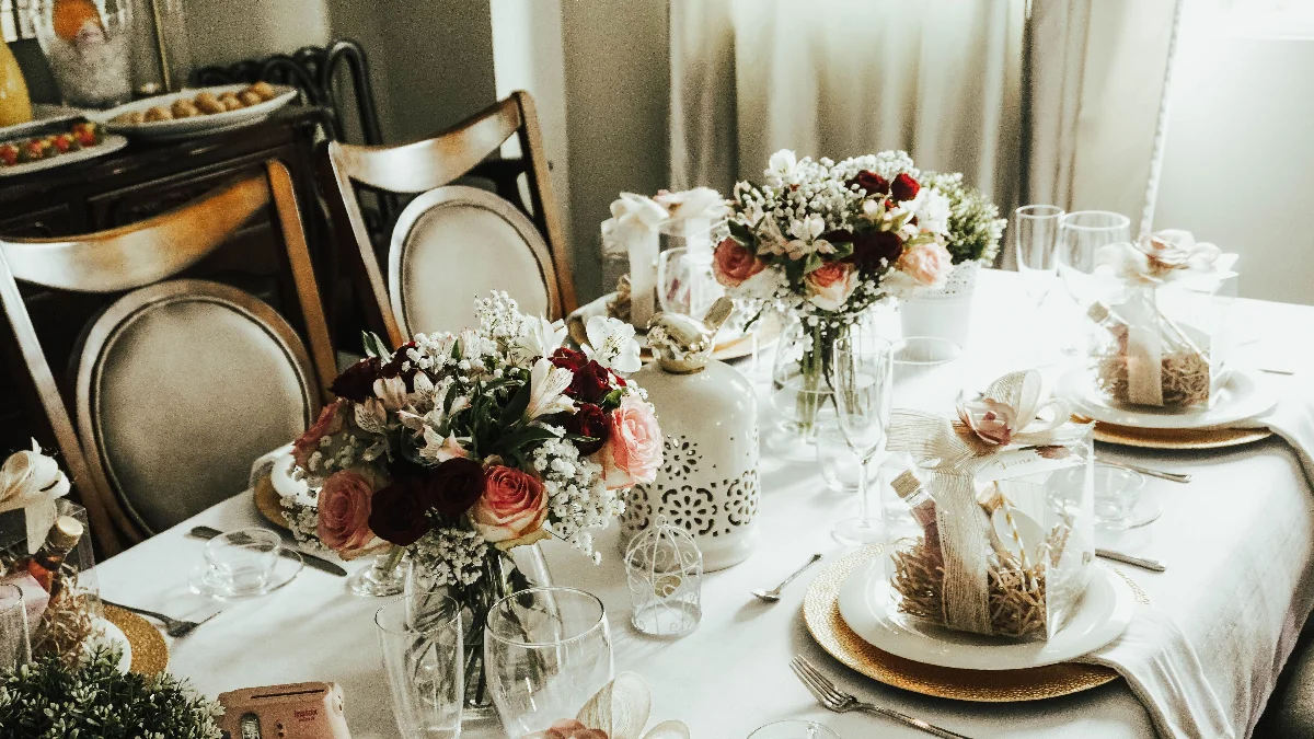 Beautifully decorated dining table with floral bouquets and gift boxes, set elegantly for a reception.