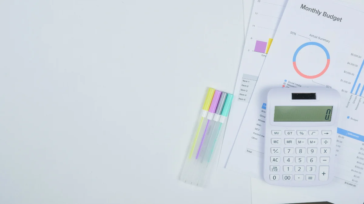 Minimalist office desk with a calculator, budget planning documents, and colorful pens.